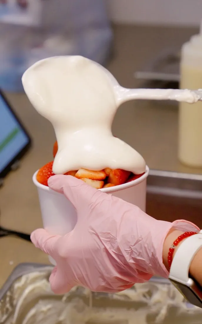 Crema cayendo sobre fresas recién cortadas