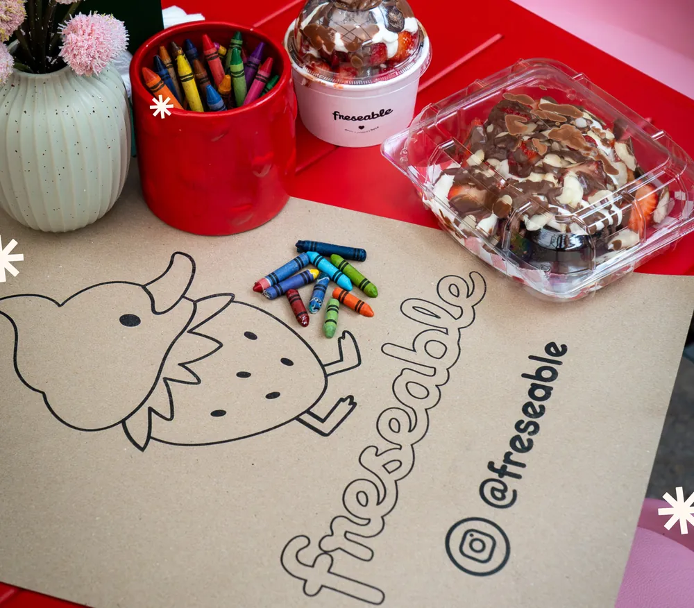 Mantel para colorear a Patricia con crayolas junto a unas fresas con crema